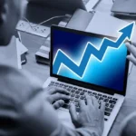 A man focused on a laptop featuring an upward arrow, representing investment growth in 5starsstocks.com passive stocks